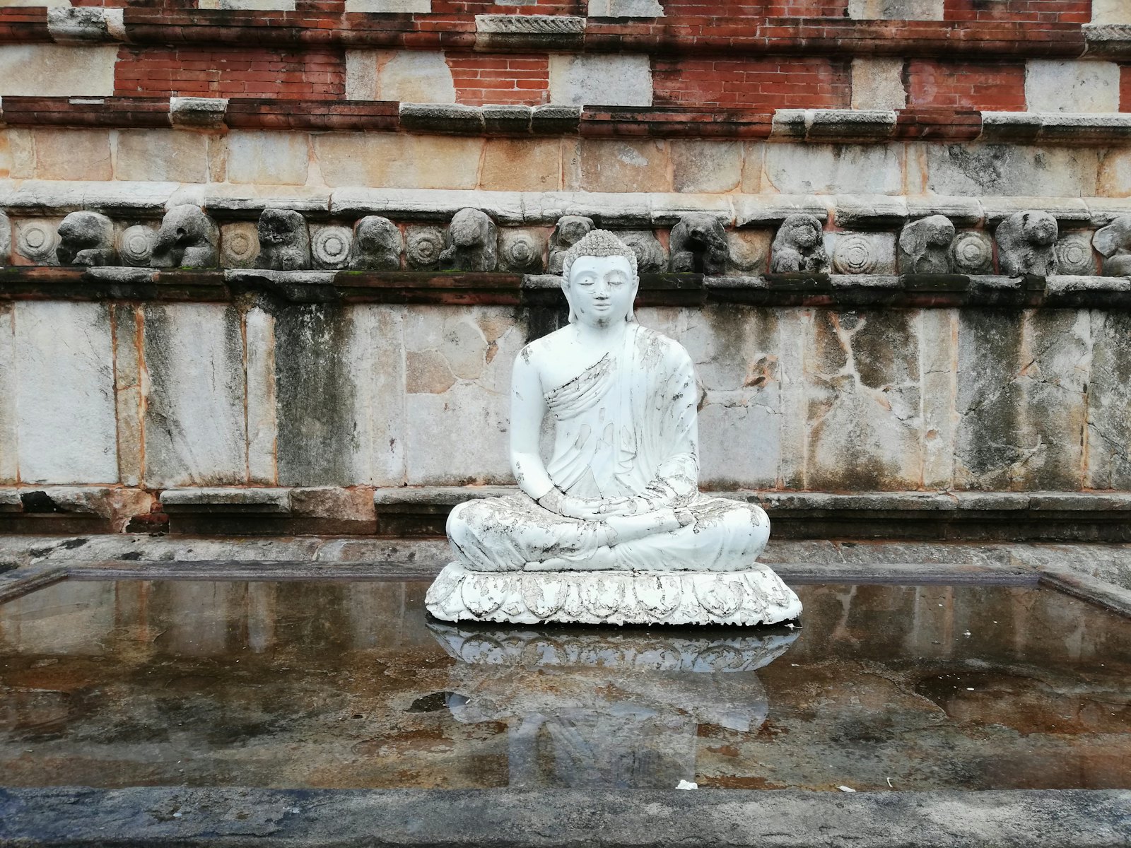 Buddha statue at peace beside still water